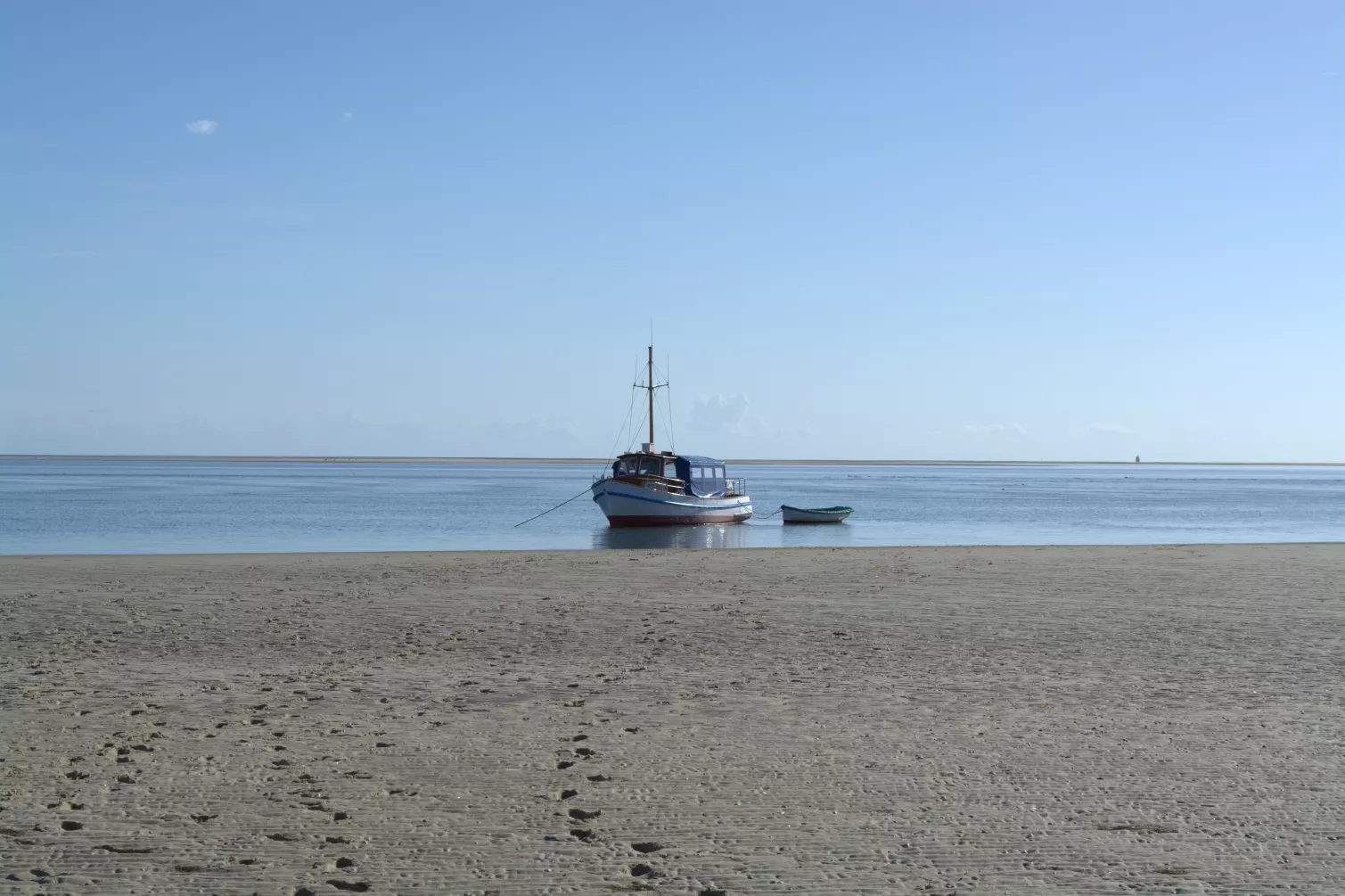Ausflugboot an einer der Sandbänke – Spuren im Sand und Blick aufs Meer bei klarem Himmel