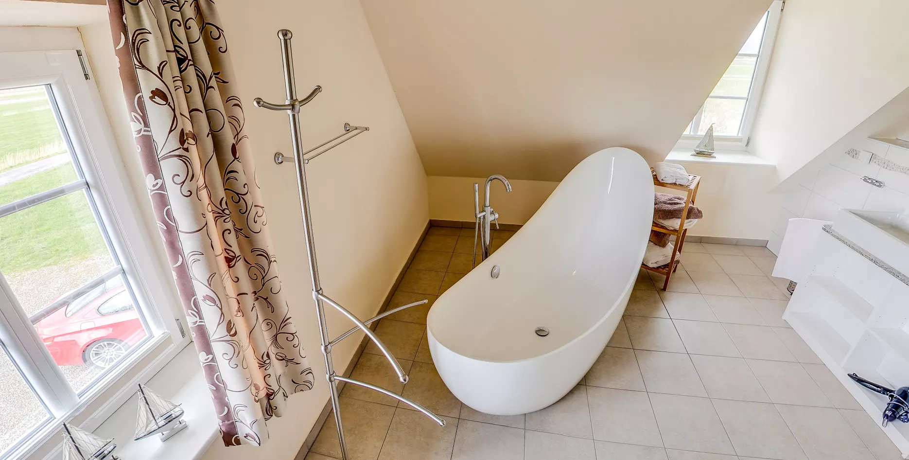 Modernes Badezimmer mit freistehender Badewanne, Fenster mit maritimer Deko und Handtuchregal.