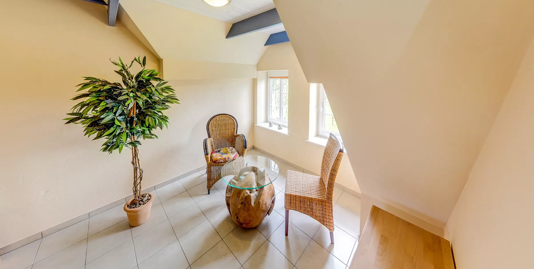 Gemütlicher Sitzbereich mit Korbstühlen und Glas-Couchtisch