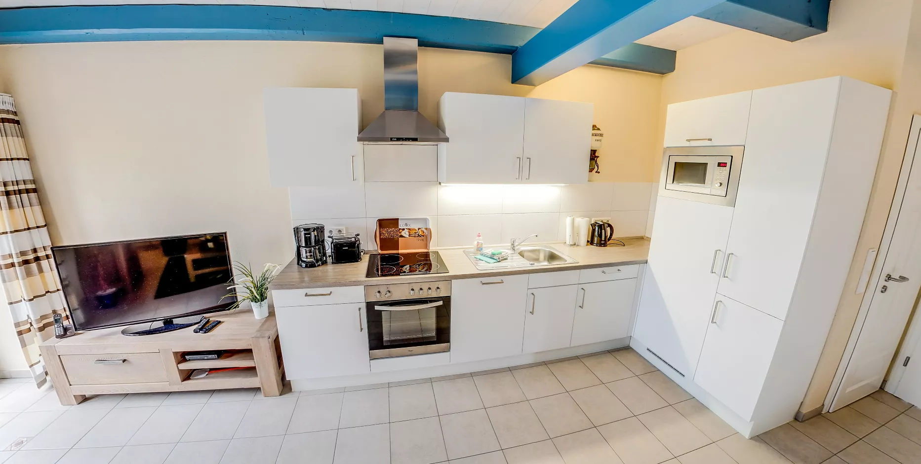 Moderne Einbauküche mit weißen Fronten und integriertem Wohnbereich