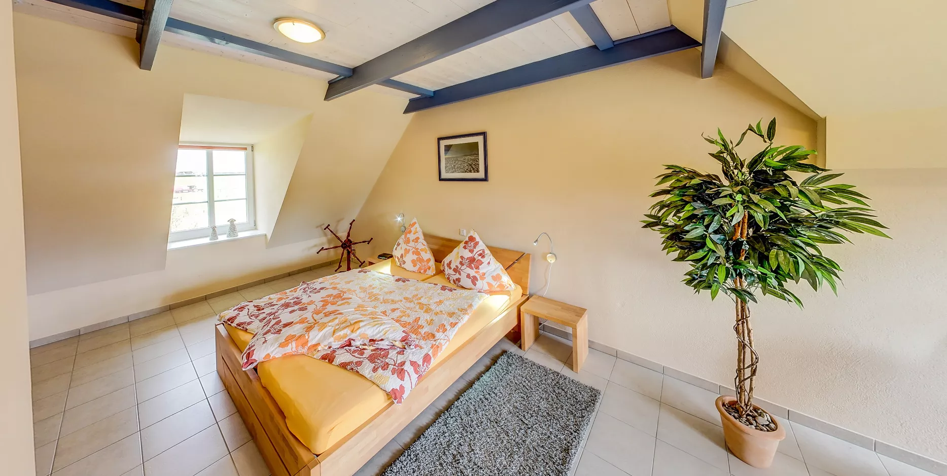 Schlafzimmer mit gelber Bettwäsche und blauen Deckenbalken