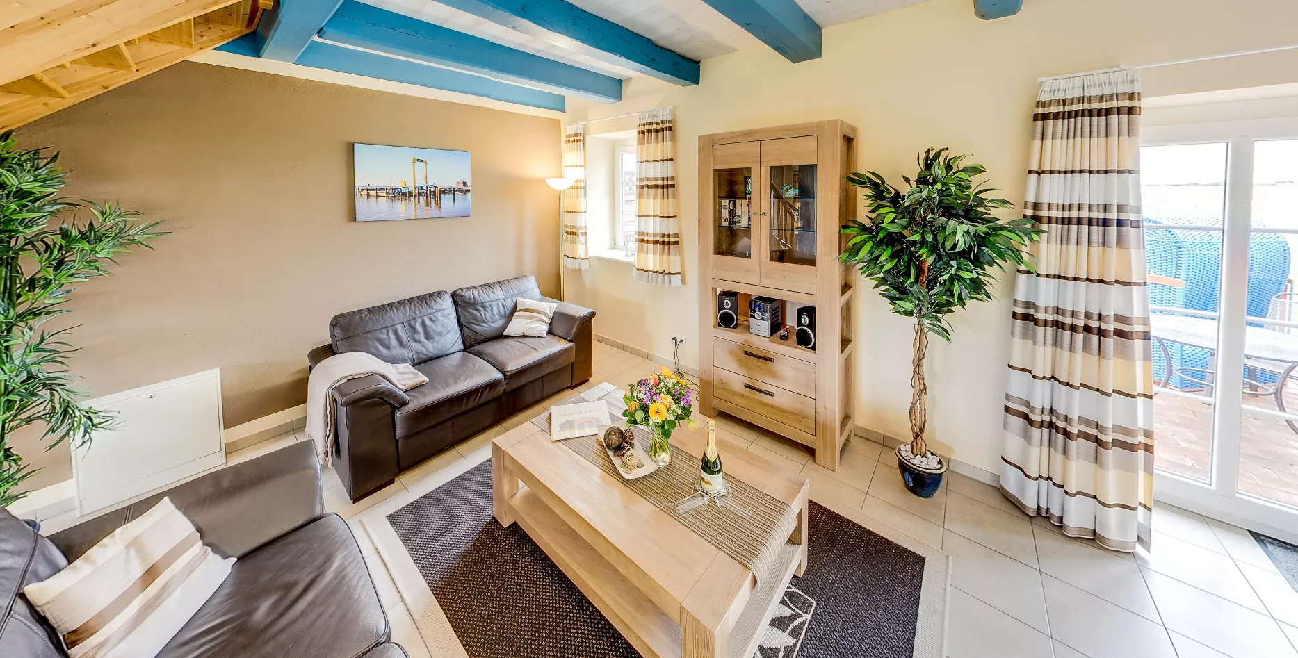 Gemütliches Wohnzimmer mit zwei Ledersofas und blauen Deckenbalken