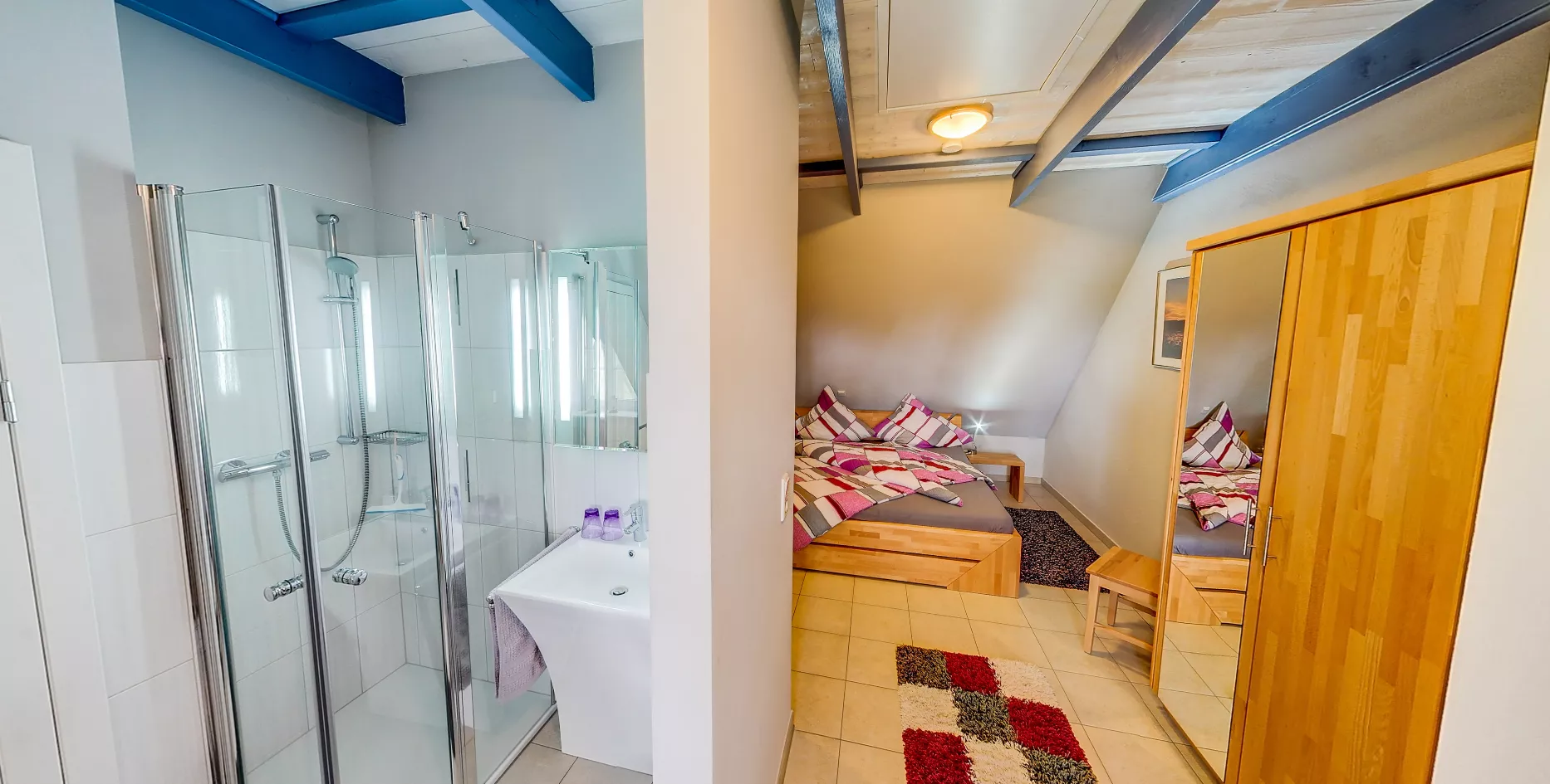 Schlafzimmer mit angrenzendem Badezimmer und buntem Teppich