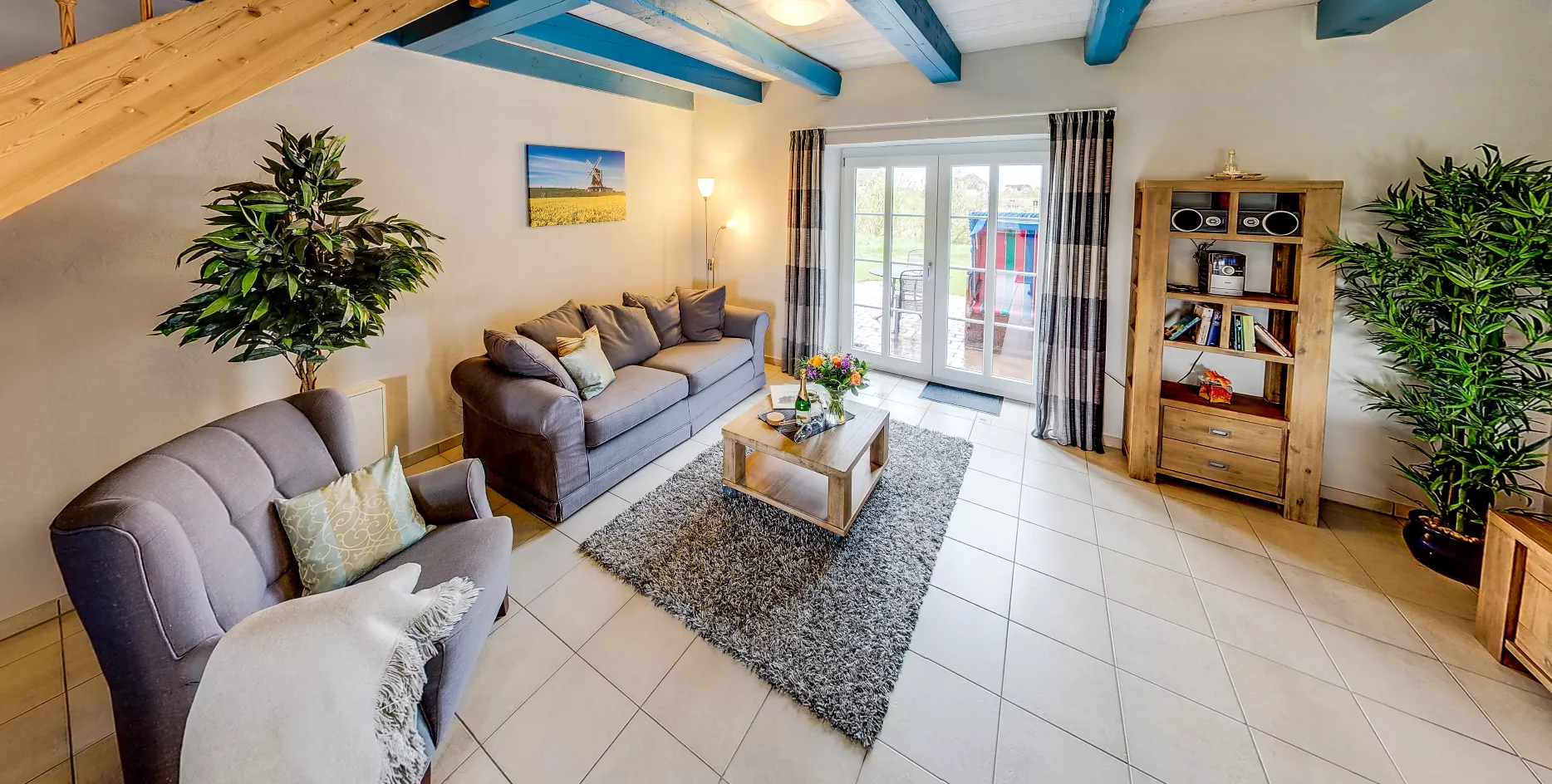 Wohnbereich der Ferienwohnung Seegarden – Ledersofas, Esstisch und geschwungene Treppe