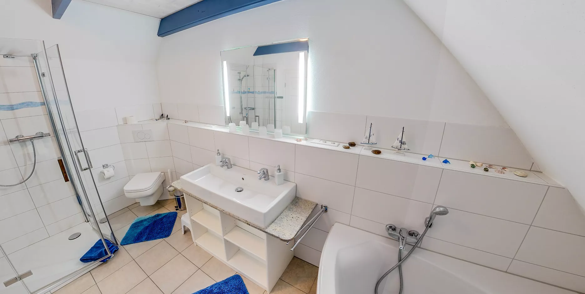 Badezimmer der Ferienwohnung Vogelkoje – Dusche, Badewanne und maritime Deko mit Segelbooten