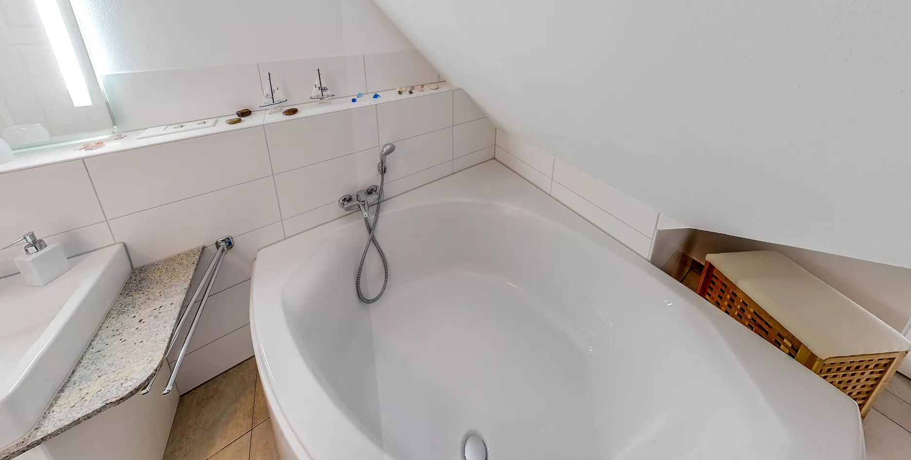 Badezimmer mit Eckbadewanne unter Dachschräge und maritimer Dekoration